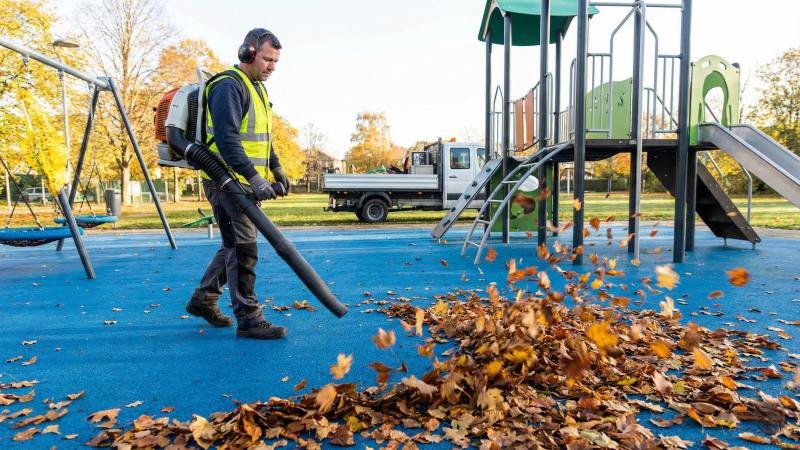 Maintenance Worker Cleaning Playground Surface With Leaf Blower