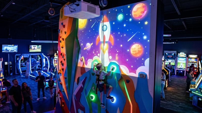Child interacting with a gamified climbing wall projected game