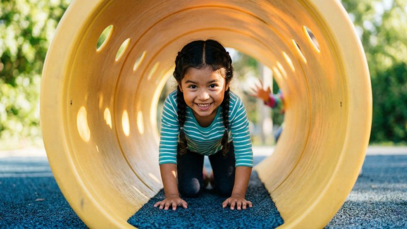 happy child crawling inside colorful playground tunnel